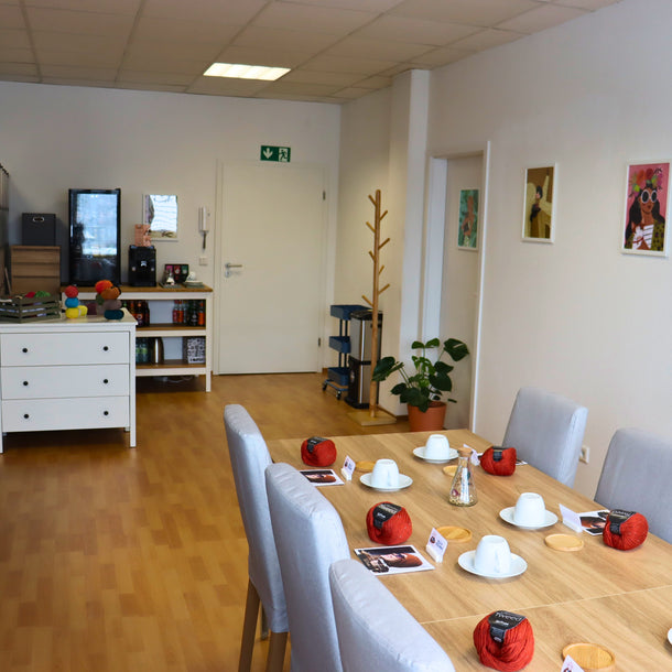 Workshopbereich mit Kaffee-Ecke, Topfpflanzen und farbenfrohe Illustrationen, Wolle und Strickanleitungen